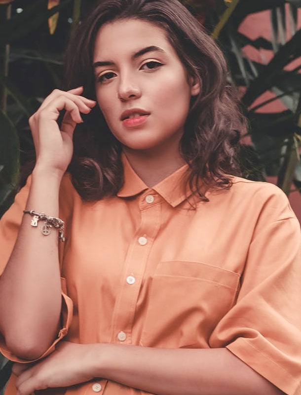 Woman in orange shirt standing in front of a plant